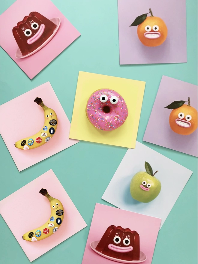 A colourful collection of square cards. A happy jelly, a pink doughnut, orange, apple and a banana  