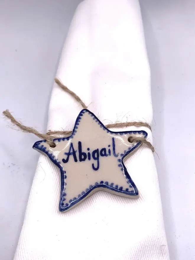 Personalised Ceramic Christmas Star Name Place Markers, a colourful star place marker sitting on a plain white surface. 