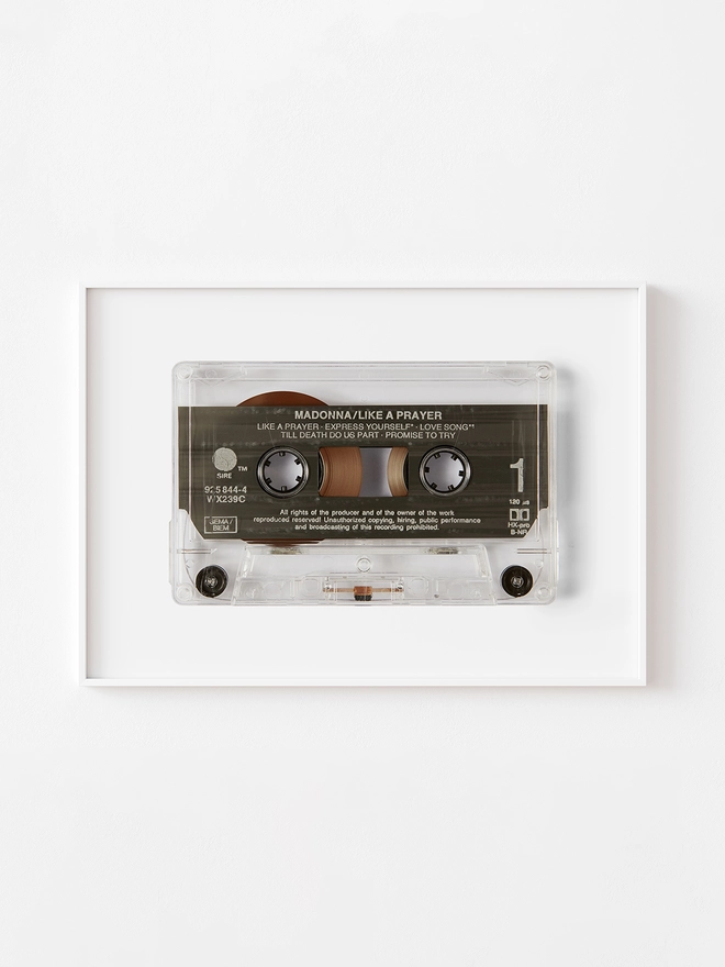 like a prayer madonna cassette tape print. framed print hung up on white wall.
