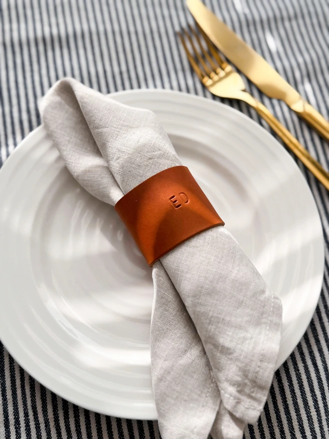 tan leather napkin ring with 'Ed' stamped on it