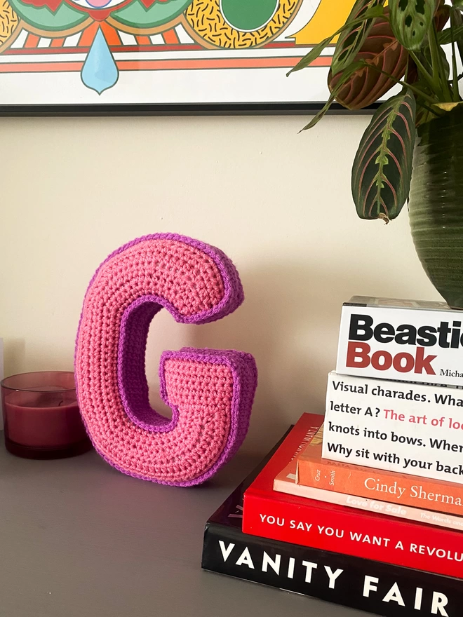 Crochet cushion shaped like the letter G in Pink and Magenta