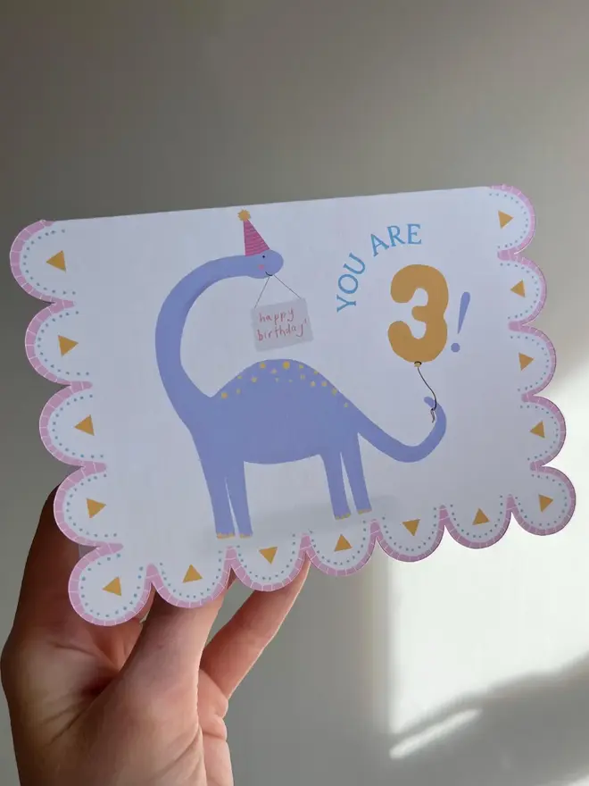 illustrated dinosaur birthday card. scallop edged card illustrated with stegosaurus.