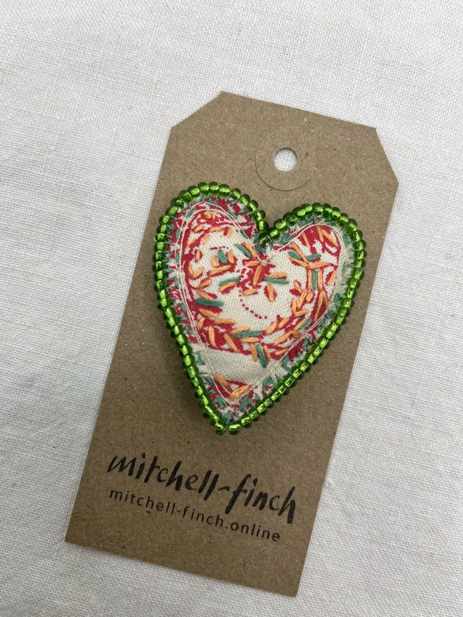 green beaded brooch on brown label