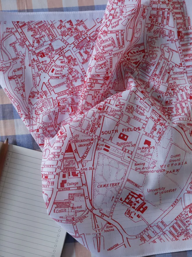 Detail of a Mr.PS Leicester map handkerchief, printed in red, alongside a lined notebook