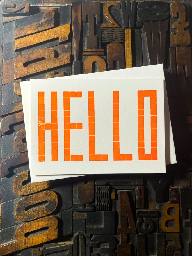 Letterpress HELLO postcard printed from a grid of square wooden type blocks in fluorescent yellow ink, deeply impressed on thick 350gsm Colorplan Pristine White card.