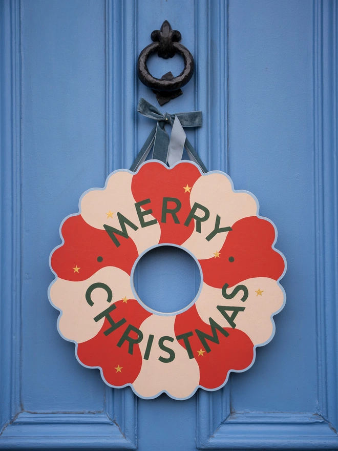 Red and pale pink Hand painted Christmas Wreath with gold leaf stars on a blue front door