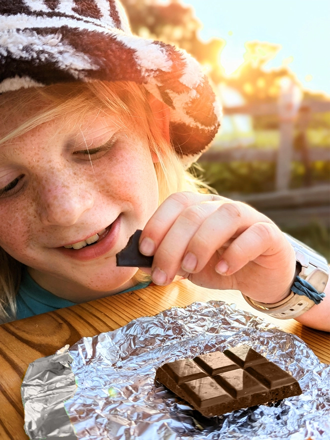 Young child opening silver foil wrapped charity milk chocolate bar with salted caramel 