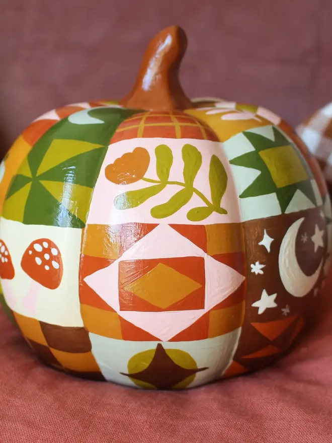 hand-painted woodland ceramic pumpkin. a ceramic pumpkin painted with patchwork colours and patters, alongside mushrooms, moons, stars and flowers.