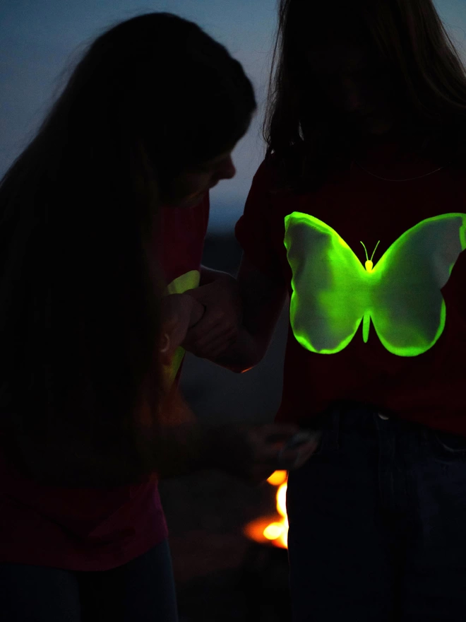 Girl drawing with torch onto butterfly glow in the dark tshirt
