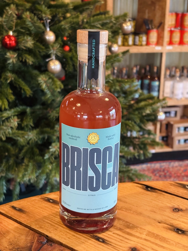 Brisca Non Alcoholic Cocktail standing on a table with a Christmas tree in the back