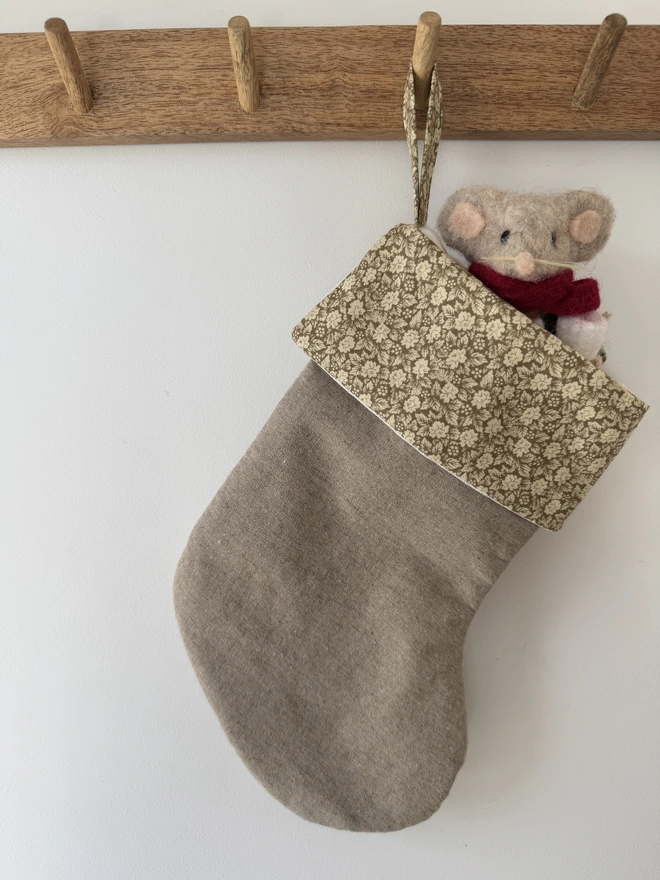 Green floral Mini Christmas Stocking. Toy mouse poking out of the top of the stocking hung from a rail