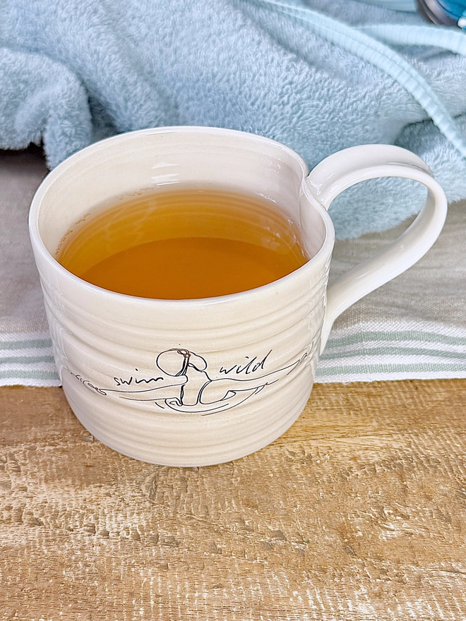 Handcrafted porcelain ‘Swim Wild’ mug – unique ceramic coffee cup for swimmers, nature lovers, and outdoor adventurers.