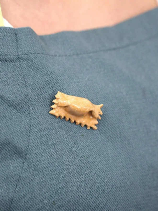 ceramic pasta pin badges. a ceramic agnolotti badge photographed on an apron.