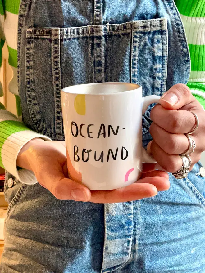 Mug reads 'OCEAN-BOUND' with colourful squiggles