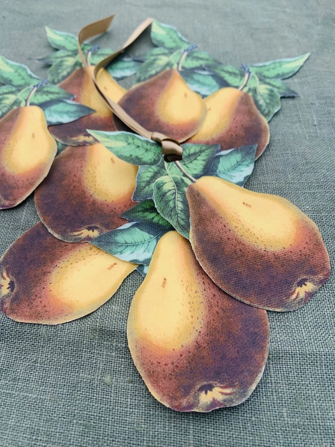 A set of festive table decorations of golden pears for place settings, on a green linen tablecloth
