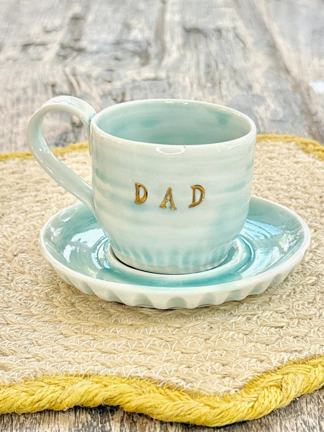 Turquoise espresso cup and saucer with a gold lustre DAD emlazoned onto the side