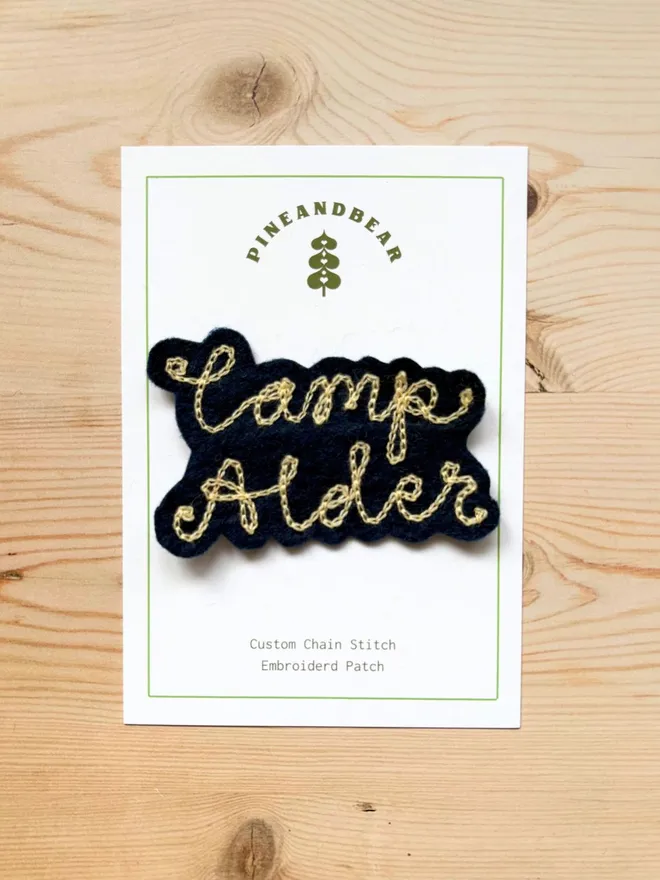 Custom chain stitch patch in navy and cream on a white presentation card