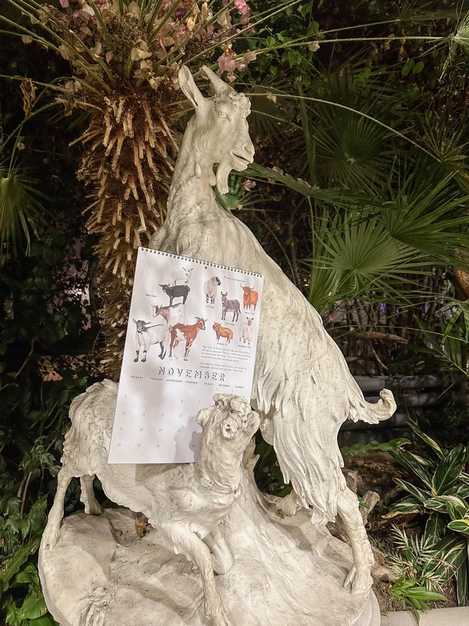 Goat calendar leaning on a statue of a goat