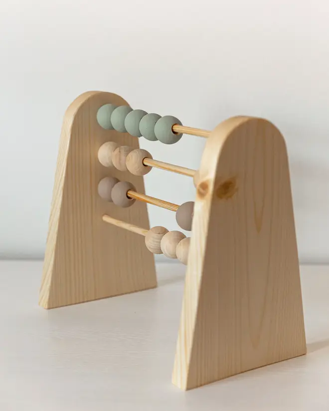 Abacus, a wooden abacus sitting on a plain surface against a white backdrop. 
