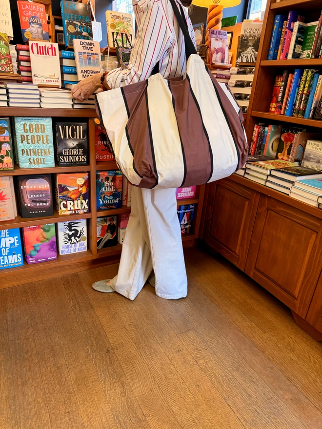brown striped tote on woman in book shop
