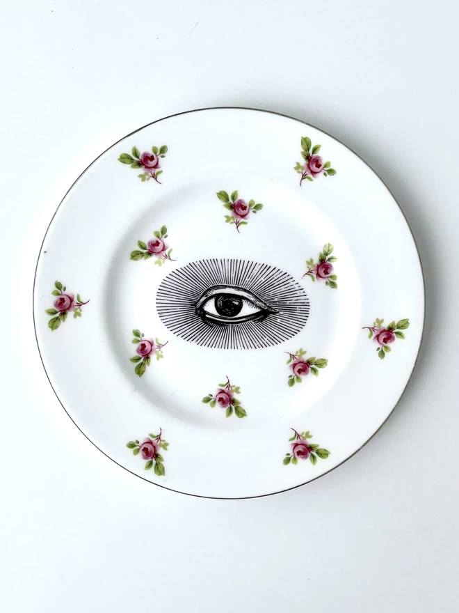vintage plate with an ornate border, with a printed vintage illustration of an eye in the middle 