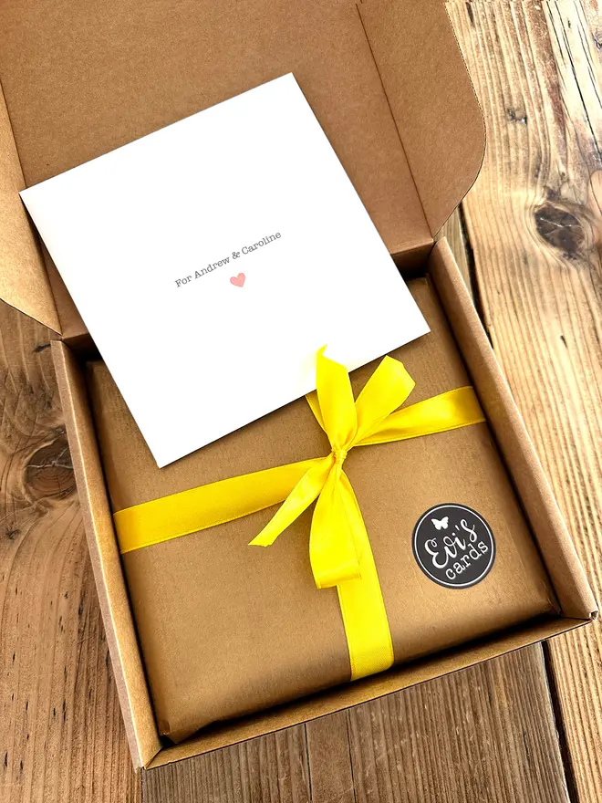 An image of a gift wrapped frame in brown paper and a silk ribbon bow in a brown paper box which is mailed direct to recipient.