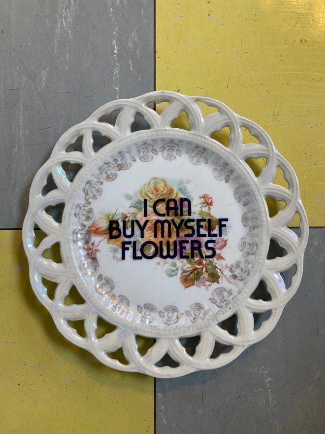 Floral vintage plate with the words 'I Can Buy Myself Flowers' printed over the top of the flowers.