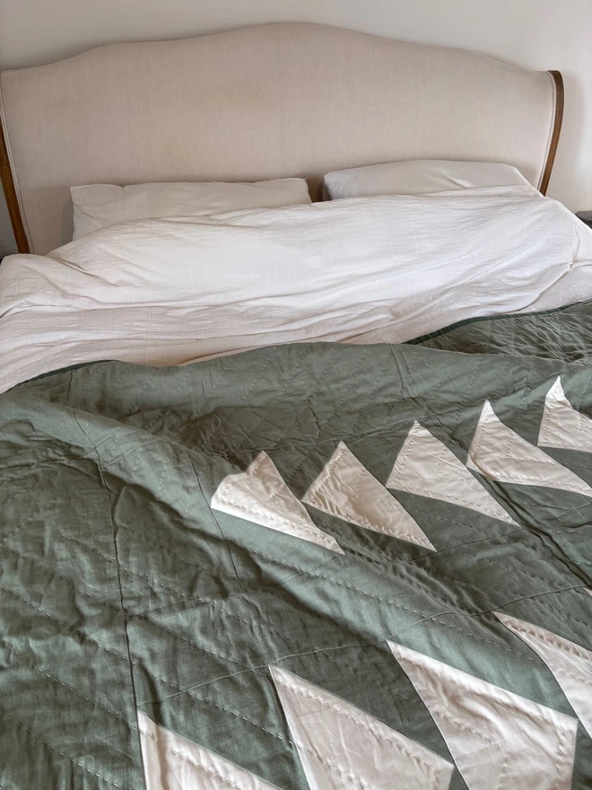 Flow Light Sage Green Linen Quilt. A green single quilt with geometric design as a throw on a king bed.