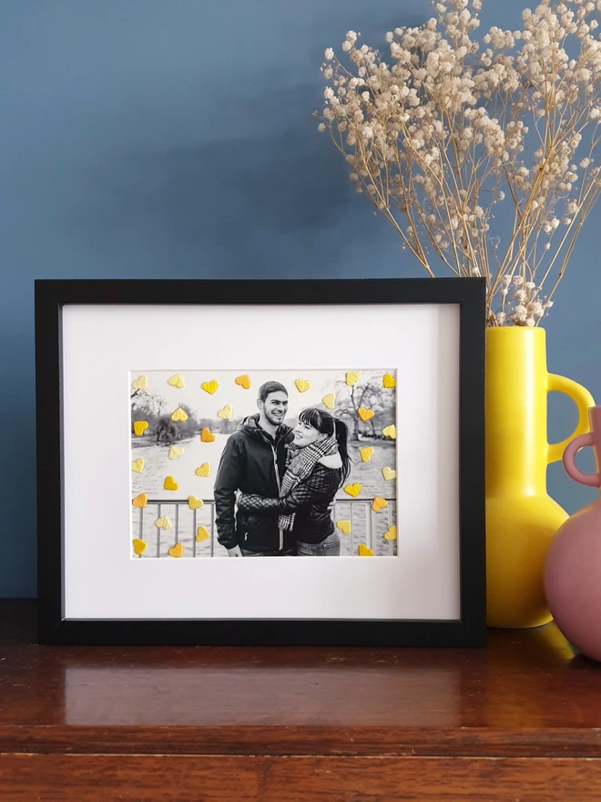 B&W couple photo, with hand embroidered shades of yellow hearts in black frame on desk