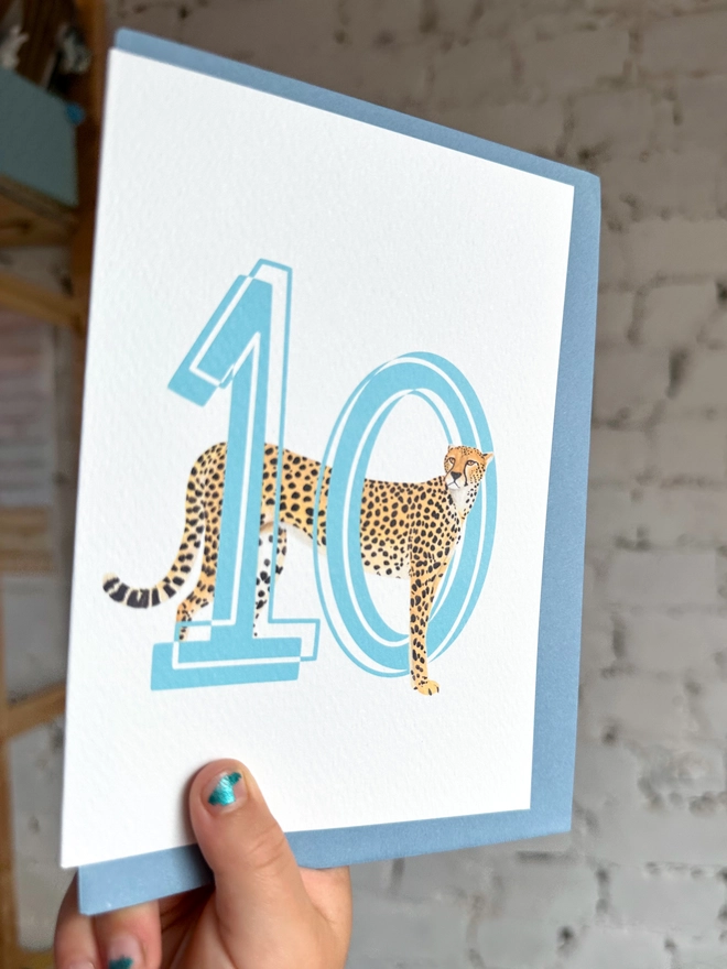 a white card with a big blue number 10 and an illustration of a cheetah with a pale blue envelope
