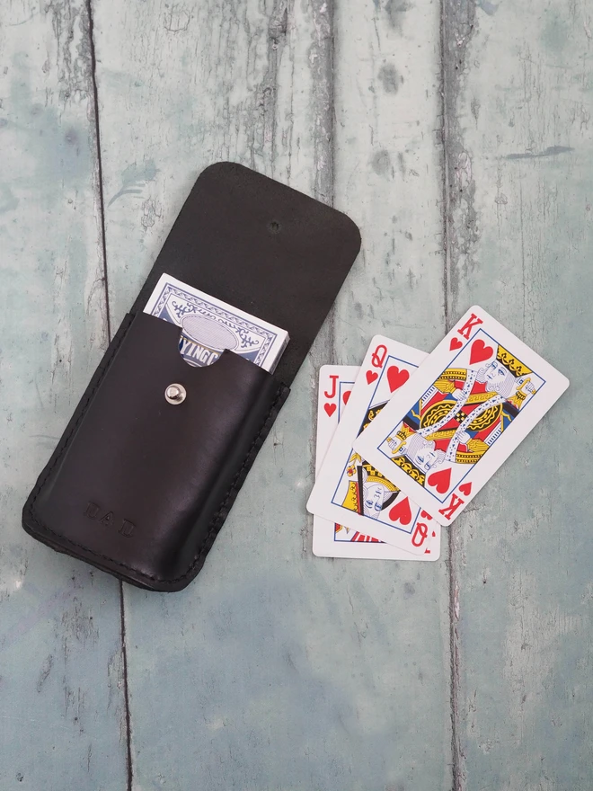 Personalised Black Leather Playing Card Holder Case. A black leather pouch with a deck of playing cards. Stamped with the name DAD on the front.