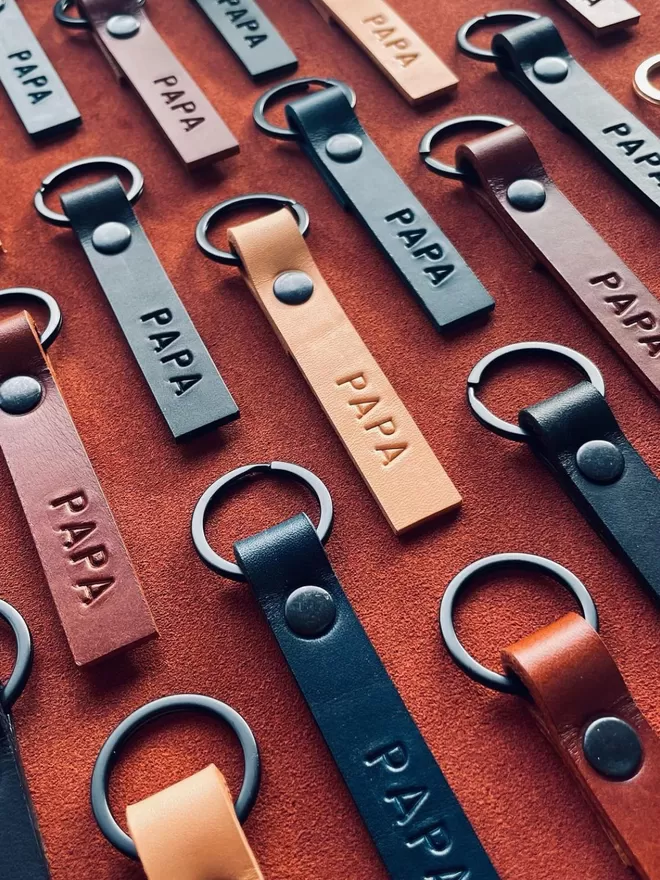 Konoc mens keyrings seen on a red surface.