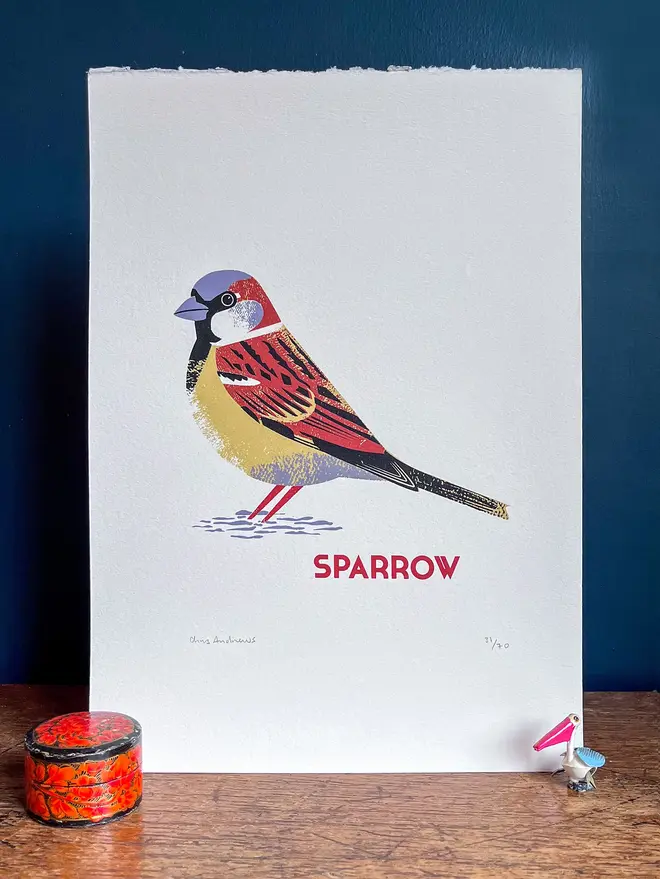 illustrated sparrow print. sparrow print propped up against navy blue wall background.