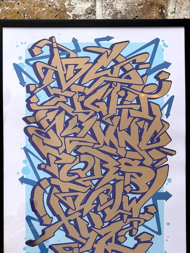 Graffiti Alphabet Metallic Gold Foil Print, framed on brick wall. 