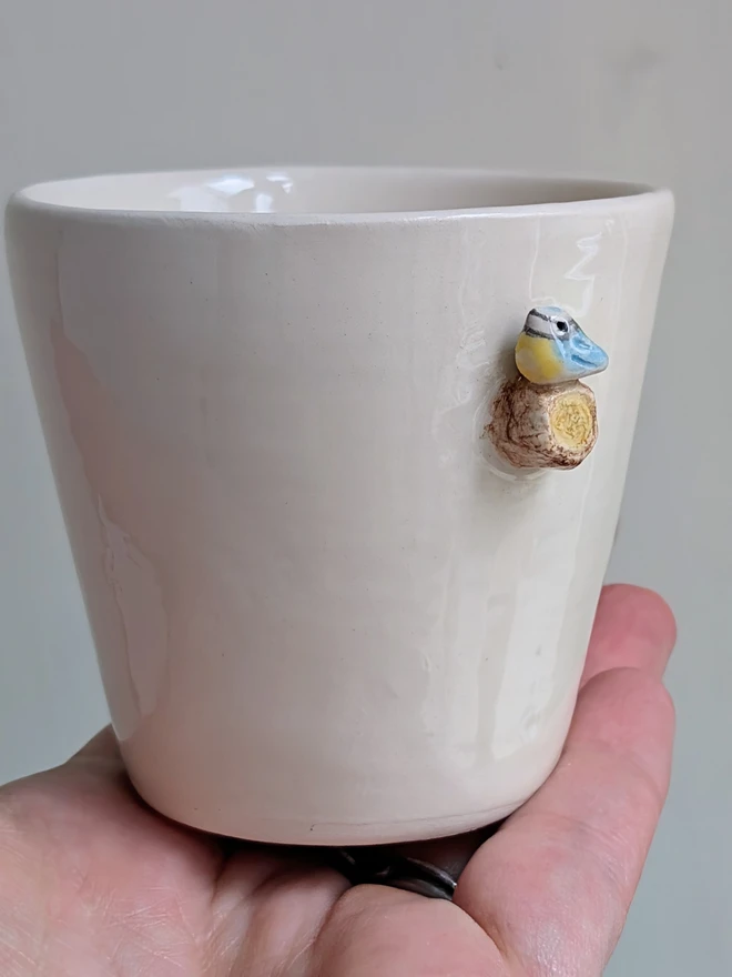 blue tit espresso coffee cup with a tiny handmade bird resting on a small ceramic tree branch in white earthenware pottery