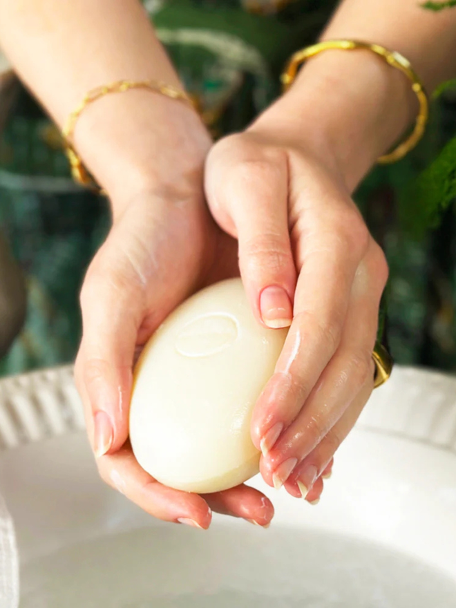 mandarin and sicilian bergamot soap bar. a handheld bar of natural soap over a basin.