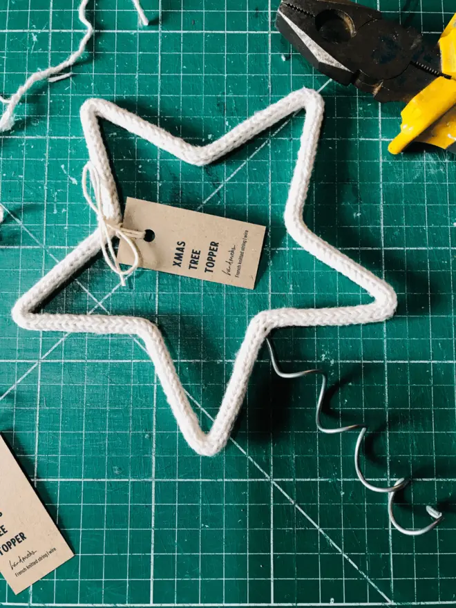 Labelled String & wire star shaped tree topper on a green cutting mat surrounded by tools