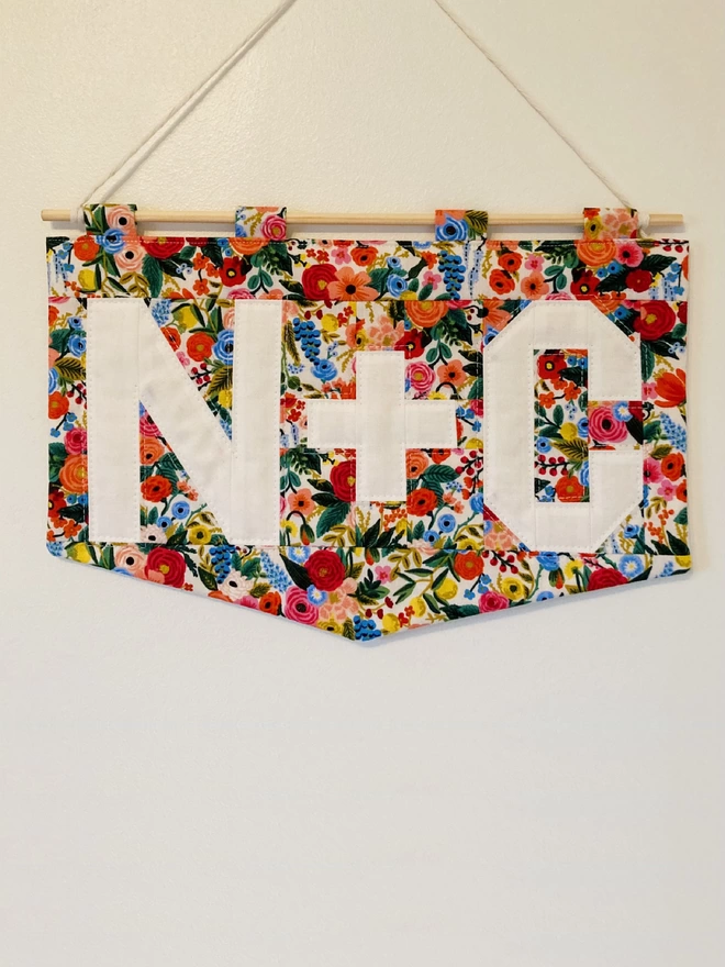 Cooper and Fred personalised quilted wall hanging with a floral background and white lettering.