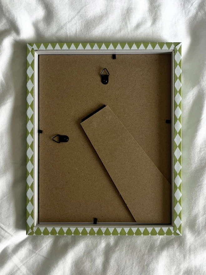 Chartreuse & Frost Harlequin Frame, the back of a colourful patterned frame sitting on a plain white surface. 