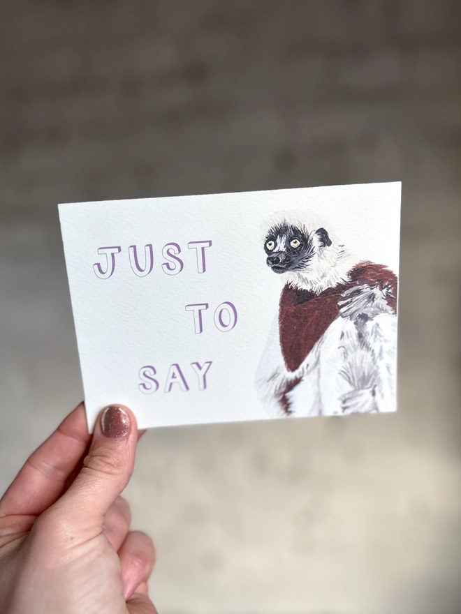  a greetings card featuring an illustration of a Coquerel’s Sifaka with the text “just to say”