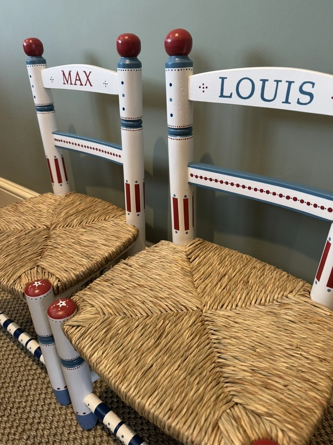 Green background with 2 chairs with hand painted names and details. 