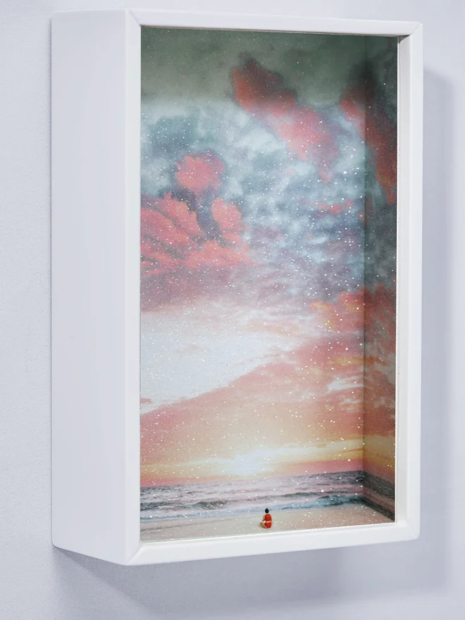 Miniature scene in an artbox showing a tiny woman 'meditating against a sparkling sunset backdrop. 