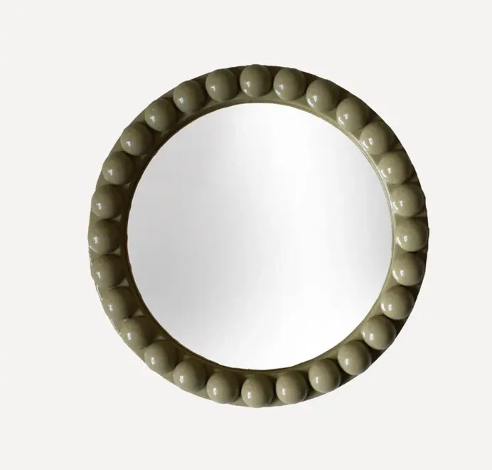 Round oversized bobbin mirror with a decorative bobbin-style wooden frame, hanging on a white wall.