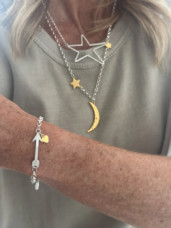 model wears sterling silver bracelet with gold arrow charm and small personalised silver heart charm