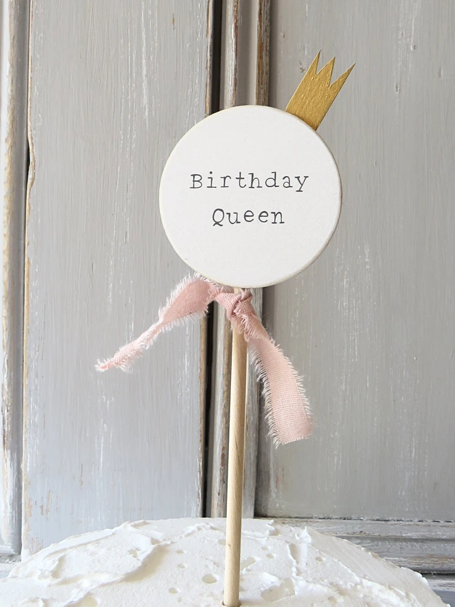 wooden circle shaped cake topper with hand painted message, gold painted crown and custom ribbon