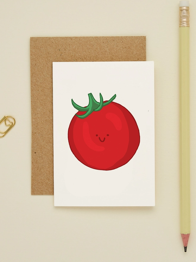 Close-up of the mini tomato card featuring a cute red tomato with a happy face, paired with a kraft envelope and soft yellow pencil on cream background