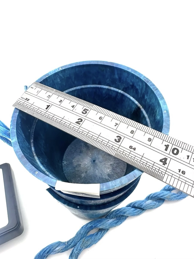 Small Blue Ocean Plastic Plant Pot , a blue recycled pot sitting on a white surface against a plain backdrop. 