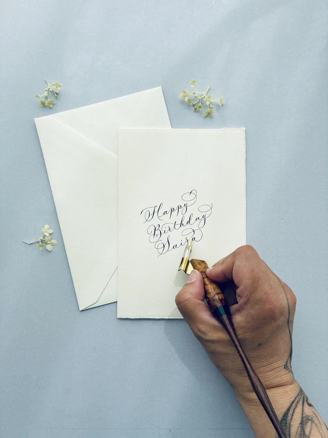 calligrapher's hand writing a birthday card