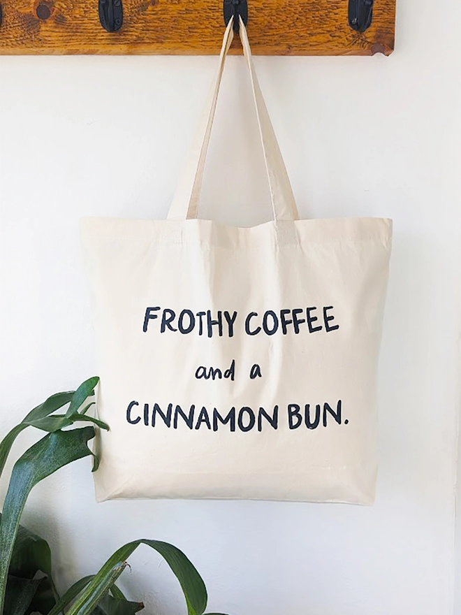 A natural coloured canvas tote with the the slogan Frothy Coffee and a Cinnamon Bun.