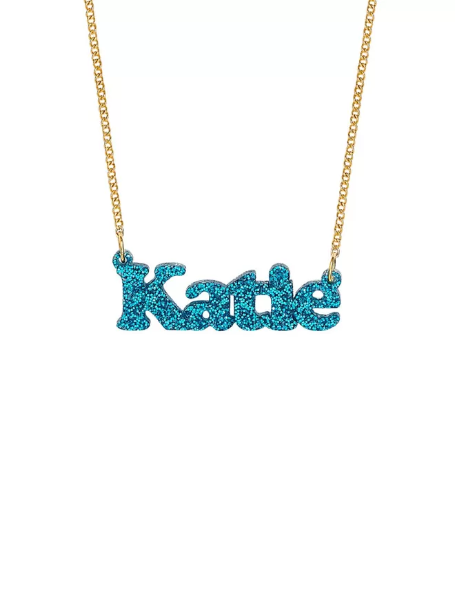 Personalised Name Neckace from Tatty Devine. The Necklace is the word Katie laser cut from Deluxe Blue Glitter Acrylic on a gold-plated chain.